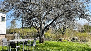A patio with a table and chairs, a large tree, and a building in the background. - 6 Person Holiday Home in Bollebygd-by Traum (Bollebygd)