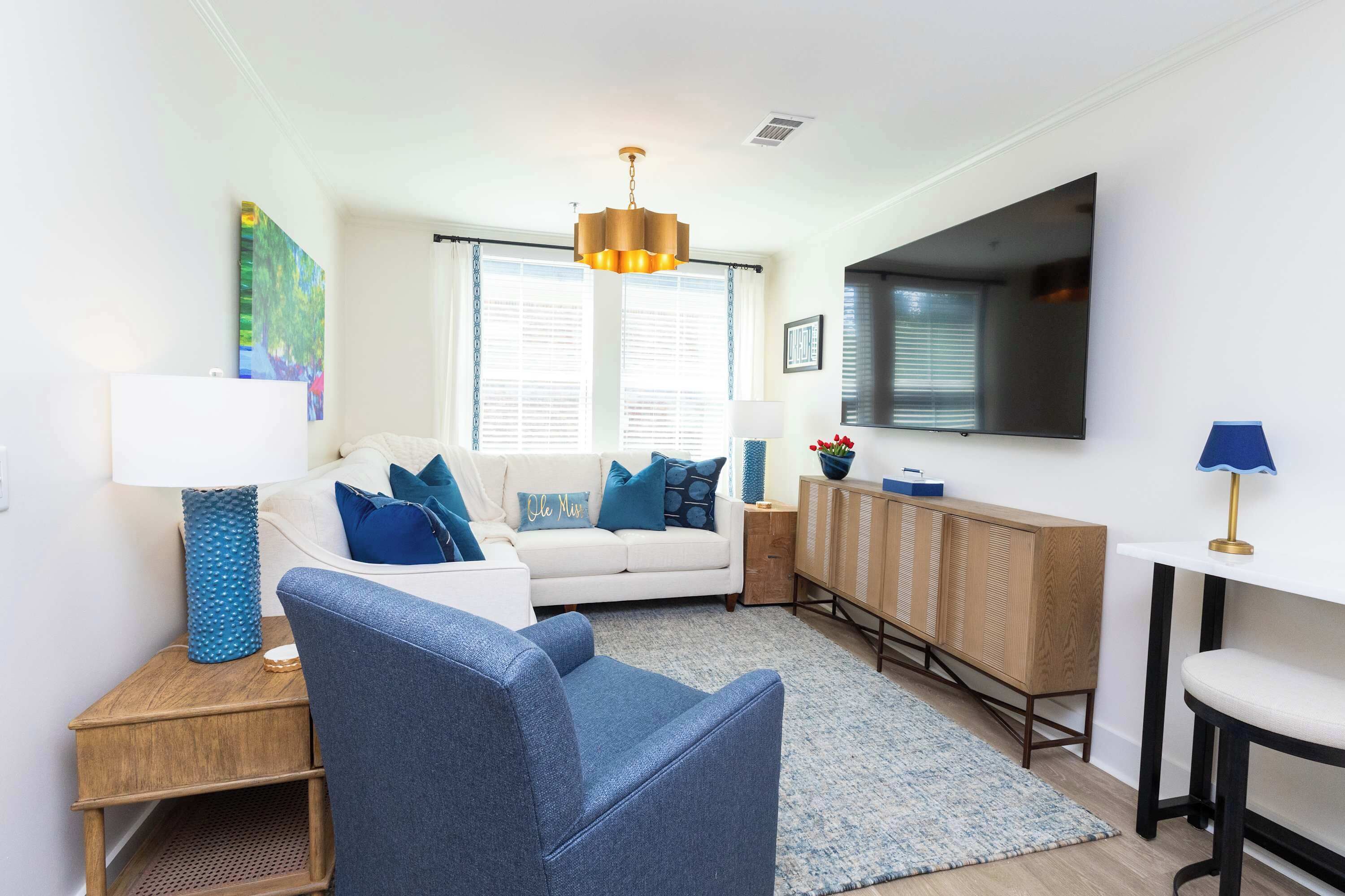 A modern living room with a sofa, armchair, and a TV mounted on the wall.