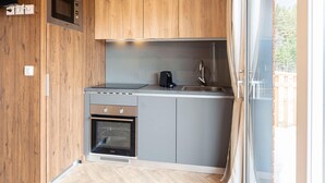 A compact kitchen with wooden cabinets, a built-in microwave, a stove, and a sink. - Beautiful Tree House in the Gailtal Valley (Kotschach-Mauthen)