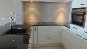 A modern kitchen with a black countertop, white cabinets, a built-in oven, and under-cabinet lighting. - Apartment in Nieuwpoort by the Beach (Nieuwpoort)