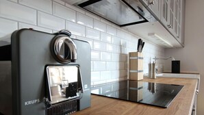 A modern kitchen with a Krups espresso machine, white tiled backsplash, and wooden countertop. - Captain House Wangerooge - Nautik Suite (Wangerooge)