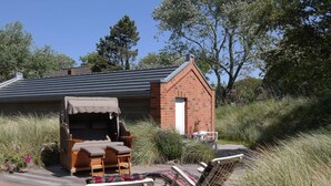 A wooden deck with lounge chairs and a small brick structure. - Captain House Wangerooge - Nautik Suite (Wangerooge)