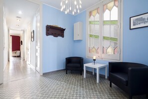 Una stanza con pavimento decorato, una poltrona nera, un tavolo bianco e una finestra con vetrate artistiche.