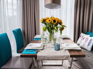 A dining table set with plates, cutlery, and a centerpiece of sunflowers. - Holiday Apartment Strandgut 16.1 (Heiligenhafen)