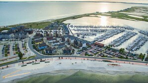 Vue aérienne d’une zone côtière comprenant un port de plaisance, des immeubles résidentiels et un parking.