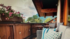 A wooden deck with a sofa and cushions, a small table, and a wooden cabinet. - Apartment in Garmisch-partenkirchen (Garmisch-Partenkirchen)