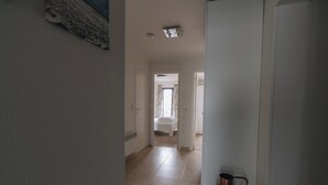 A hallway with a bed in the background, a radiator, and a copper water jug. - Apartment Nieuwpoort Near Beach Promenade (Koksijde)