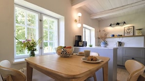 Una mesa de madera con sillas, un florero con flores y un croissant en un plato.