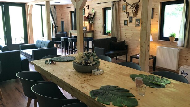 Un intérieur en bois comprenant une table à manger, des chaises, des canapés et une cheminée.