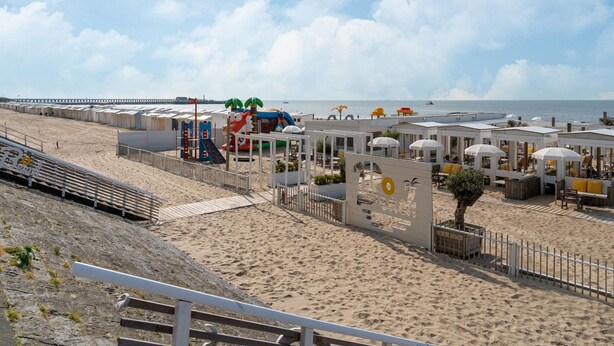 A beachside hotel with multiple rooms, a playground, and a pier in the background. - Beachside Holiday Retreat in De Haan (De Haan)