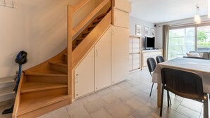 A modern kitchen with a wooden staircase, a dining area, and a large window providing a view of the outdoors. - Beachside Holiday Retreat in De Haan (De Haan)