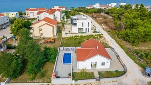 Un quartier résidentiel situé sur la côte, avec des maisons, une piscine et une vue sur la mer.