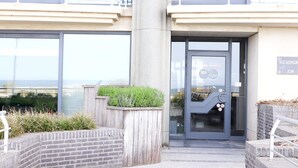 Une entrée d’immeuble avec une porte en verre, une enseigne indiquant « SEASIGHT 120 » et une vue sur la mer à travers les fenêtres.