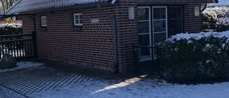 En byggnad av tegel med ett sadeltak och en liten veranda.