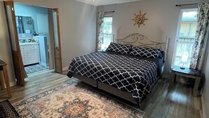 A bedroom with a bed, a ceiling fan, a rug, and a view of a kitchen and bathroom through an open door. - Hidden Gem near Lackland AFB, SeaWorld & Downtown Alamo (San Antonio)
