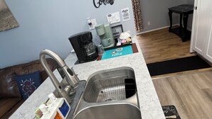 A kitchen with a sink, coffee maker, and a clock on the wall. - Hidden Gem near Lackland AFB, SeaWorld & Downtown Alamo (San Antonio)