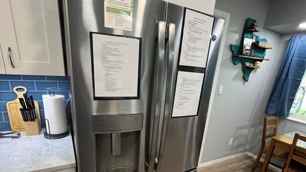 A stainless steel refrigerator with notes attached, a wooden cutting board with knives, and a paper towel holder on a kitchen counter. - Hidden Gem near Lackland AFB, SeaWorld & Downtown Alamo (San Antonio)