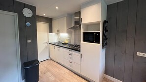 A compact kitchen with white cabinets, a black countertop, a microwave, and a gas stove. - Bungalow in Limburg Near Nature Reserve (Stramproy)