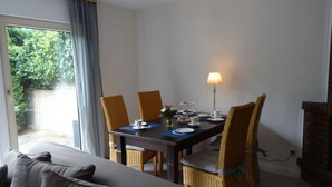 A dining area with a table set for four, chairs, a lamp, and a view of greenery outside. - Anchorage Modern Retreat (Kappeln)
