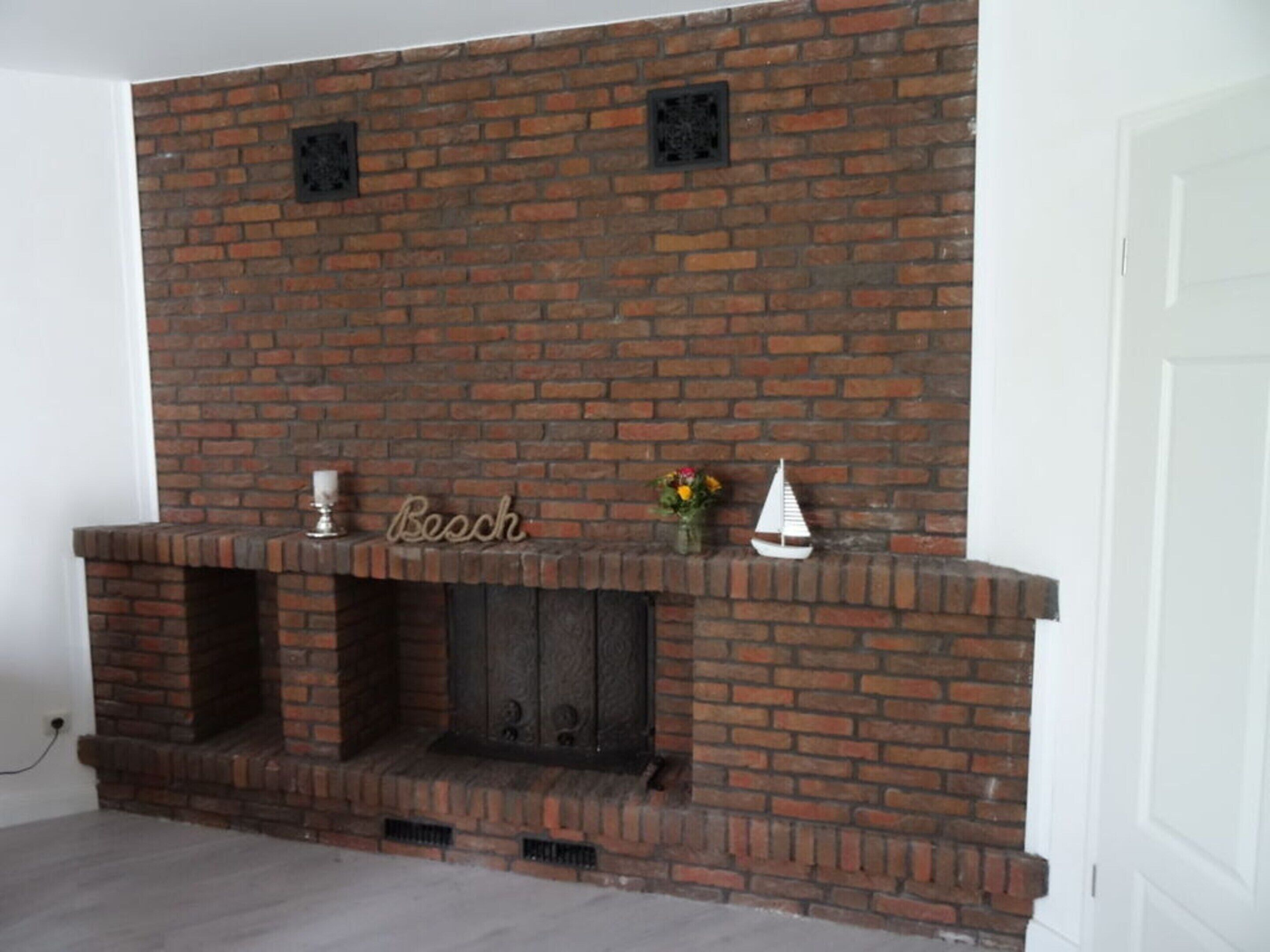 A brick fireplace with a mantel, a small shelf, and a decorative item.