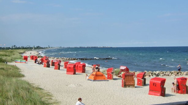A beach with red beach huts and a clear blue sky. - Anchorage Modern Retreat (Kappeln)