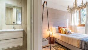 Un dormitorio con cama, mesita de noche, lámpara y una ventana con cortinas.