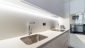 Una cocina moderna con un lavamanos de acero inoxidable, un microondas integrado y una encimera elegante.