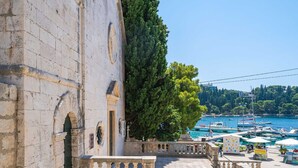 A stone building with a balcony overlooking a marina with boats. - Apartments Villa Royale - One Bedroom Apartment With Sea View (Konavle)