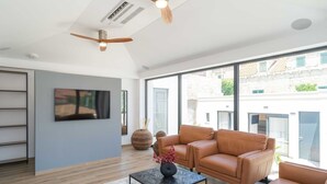A modern living room with a sofa set, a coffee table, and two ceiling fans. - Apartments Villa Royale - One Bedroom Apartment With Sea View (Konavle)