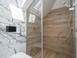 A modern bathroom with a glass shower enclosure, marble walls, and wooden flooring. - Apartments Villa Royale - One Bedroom Apartment With Sea View (Konavle)