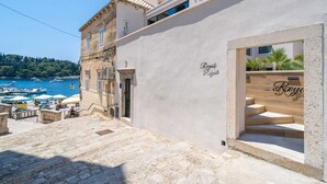 A coastal building with a stone staircase leading to a wooden door labeled "Royale." - Apartments Villa Royale - One Bedroom Apartment With Sea View (Konavle)