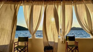 Une chambre avec vue sur la mer, comprenant deux chaises en bois et une plante en pot.