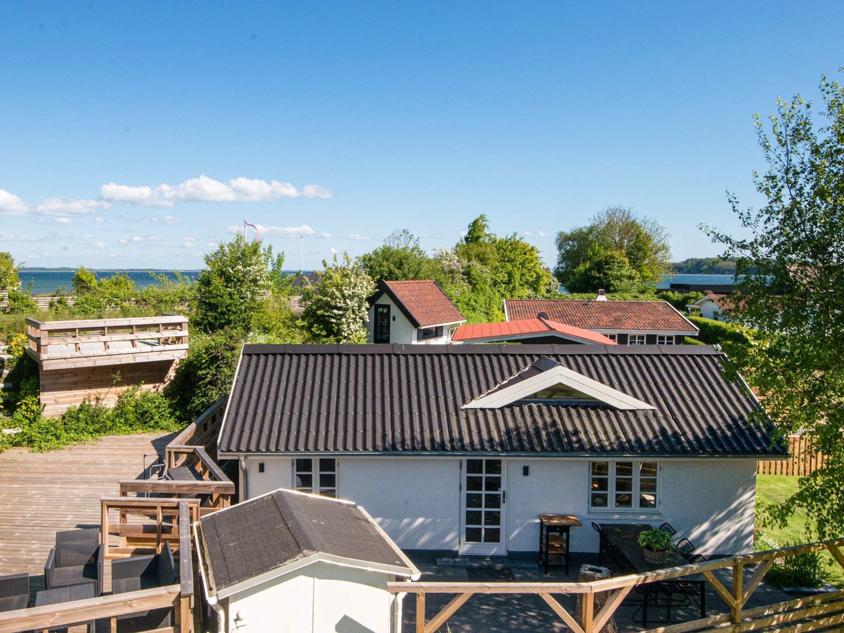 A two-story house with a sloped roof, a deck, and a view of the sea.