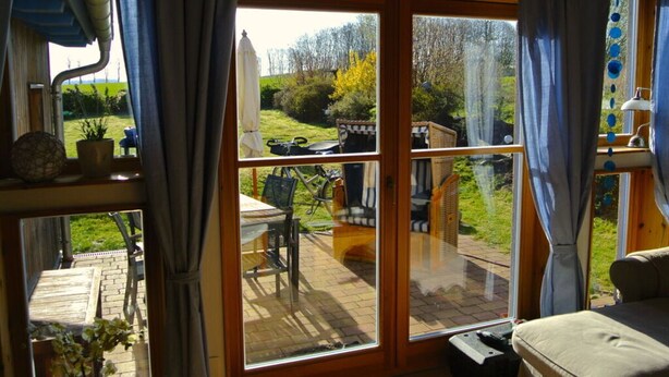 A room with a sliding glass door leading to an outdoor patio area. - WE Evening sun in the sun House (Kalkhorst)