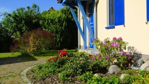 Et hus med blå skodder og en have med forskellige planter og blomster.