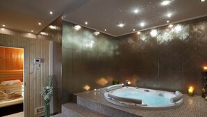 Moderni spa-huone, jossa on poreallas, puinen sauna ja laatoitettu lattia.