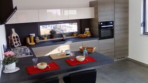 A modern kitchen with a central island, stainless steel appliances, and a window providing natural light. - Charming Apartment in Istria (Vodnjan)