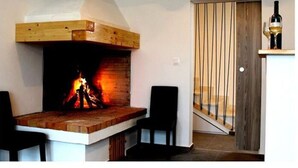 A room with a fireplace, a wooden bench, two chairs, and a door with vertical blinds. - Charming Apartment in Istria (Vodnjan)
