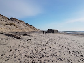 A sandy beach with footprints and a large rock formation.