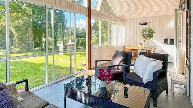 A spacious room with a large glass window, a comfortable sofa, a dining table, and a chair. - 4 Star Holiday Home in Bergkvara-by Traum (Bergkvara)