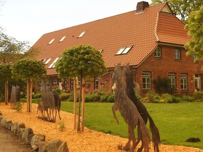 A large brick house with a tiled roof, surrounded by a well-maintained lawn and decorative metal sculptures. - Farm at Grebiner See (Grebin)