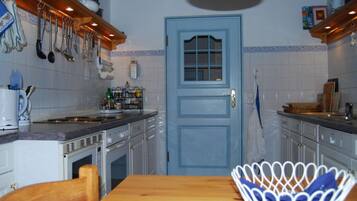 A kitchen with white cabinets, a blue door, and various kitchen utensils hanging on the wall.
