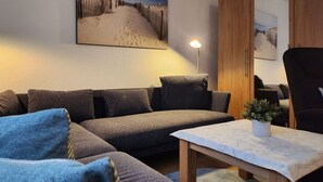 A modern living room with a sectional sofa, a small table, and a potted plant. - Sound of the sea Modern Retreat (Wangerooge)
