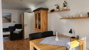 A compact living space with a dining area, a wardrobe, and a small kitchen. - Sound of the sea Modern Retreat (Wangerooge)