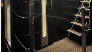 Een moderne lift met glazen deur en een metalen trap in een gebouw.