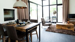 Un espace repas moderne avec une table en bois, des chaises et une grande fenêtre agrémentée de rideaux.