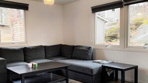 Una habitación de esquina con un sofá gris, una mesita de centro negra y una pequeña mesita auxiliar.