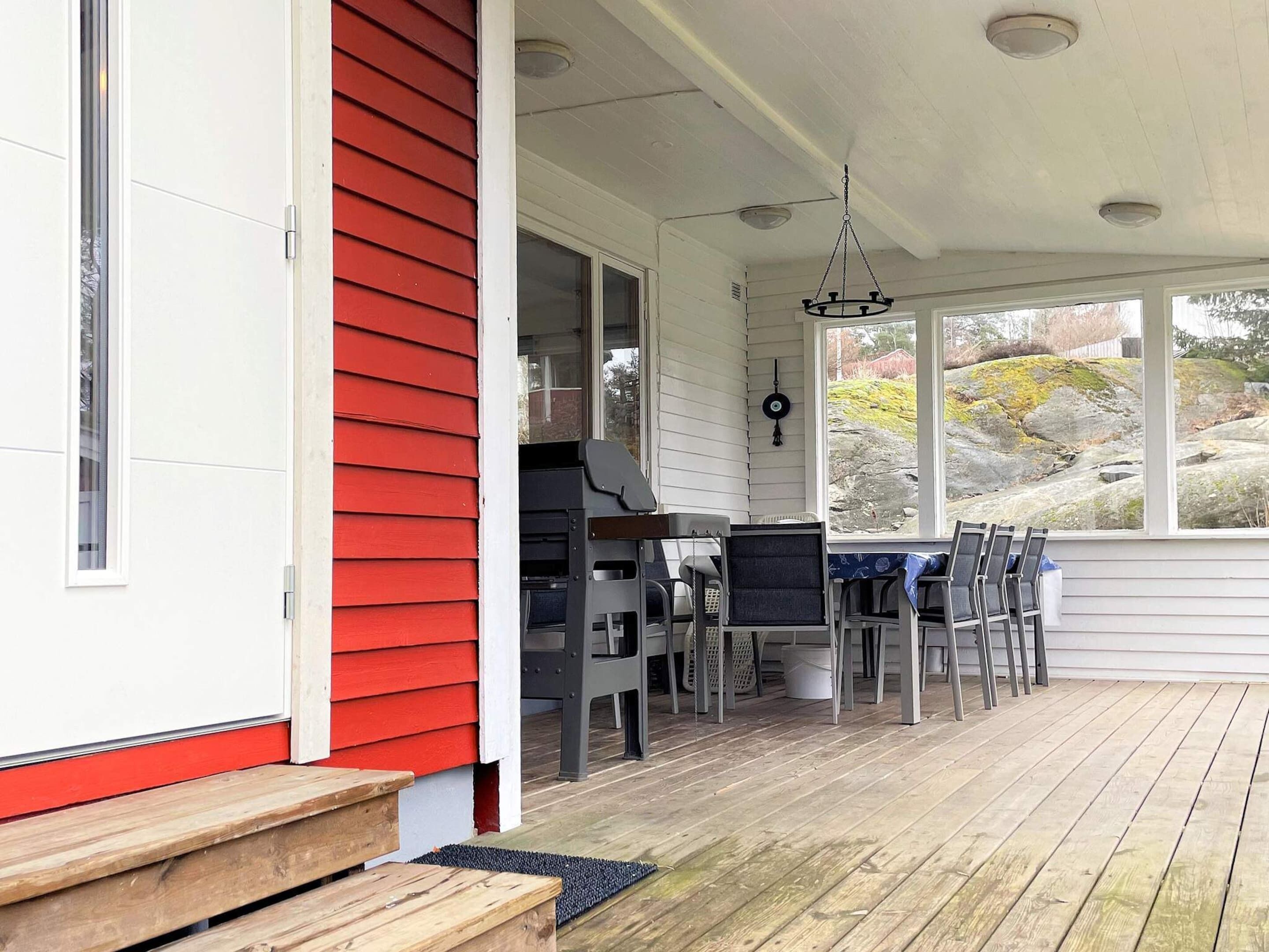 A covered porch with a dining table and chairs, a grill, and a view of the outdoors.