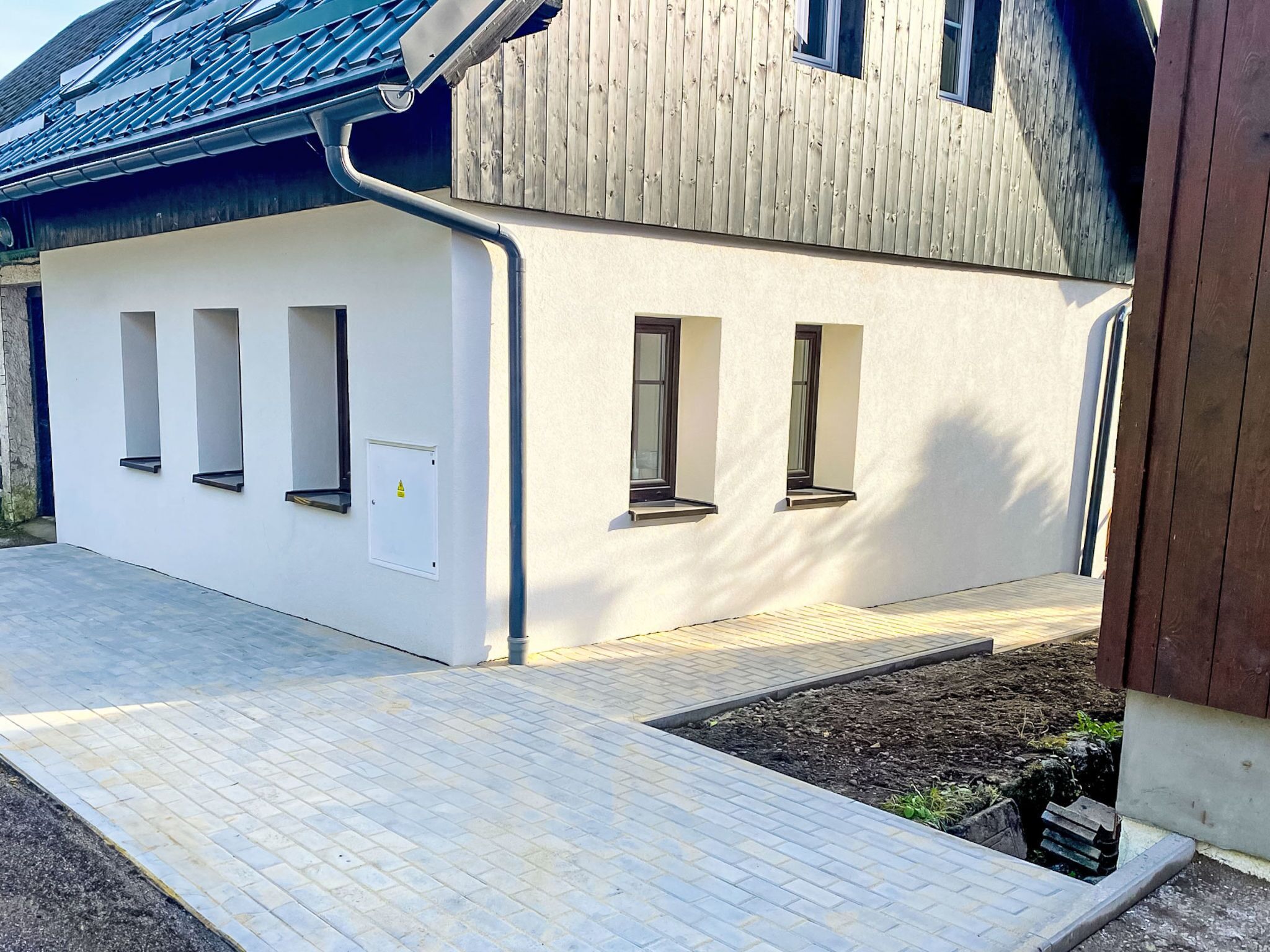 Un bâtiment moderne à la façade blanche, doté de nombreuses fenêtres et d’un toit en pente.