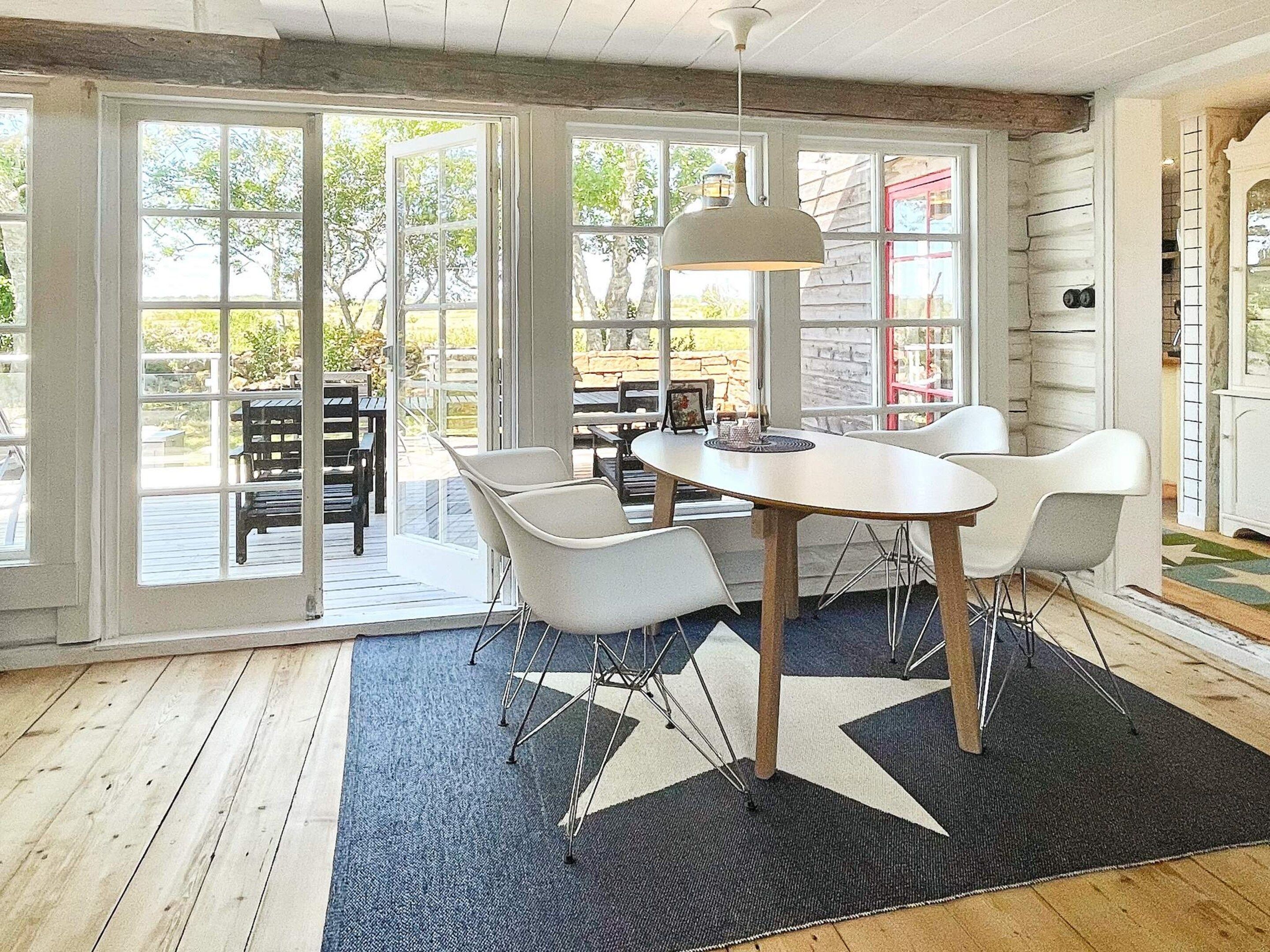 Een eethoek met een ronde tafel, witte stoelen en een hanglamp.